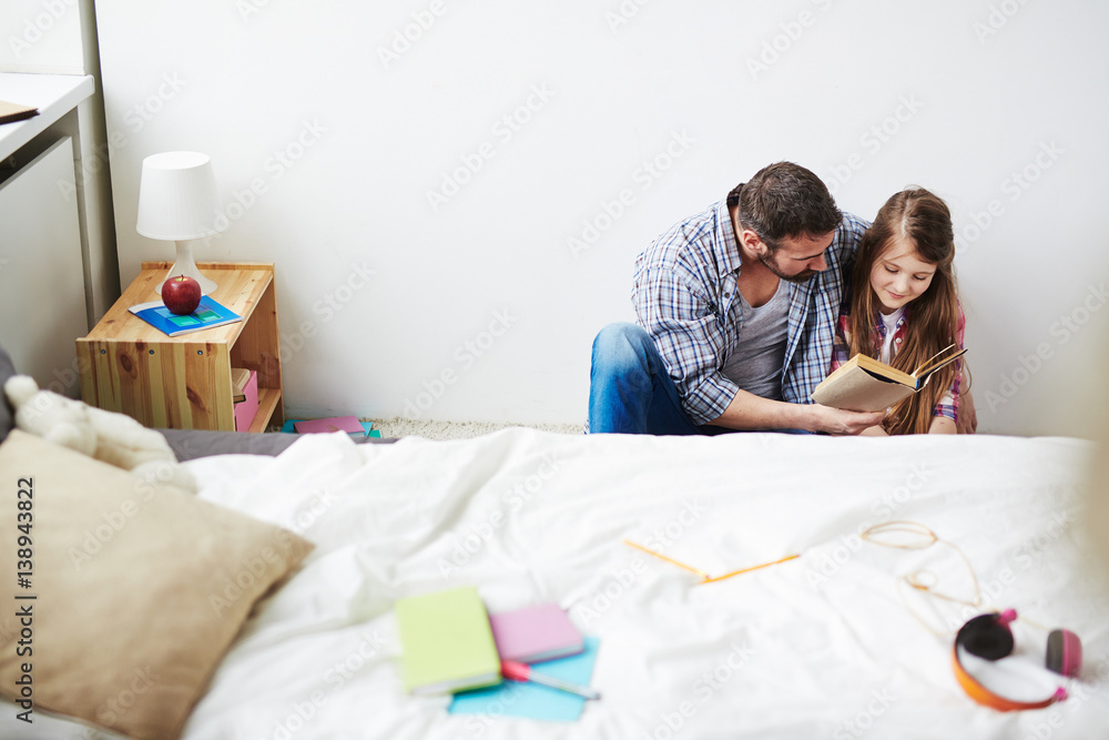 Εκτύπωση καμβά Careful middle-aged man sitting on floor with his little daughter and reading ad