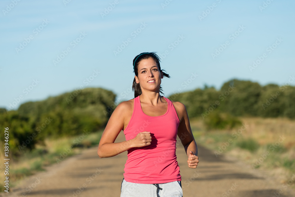 Sporty woman running on a road. Female runner training endurance outdoor on summer.
