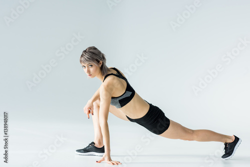 Athletic young woman in sportswear exercising and looking at camera