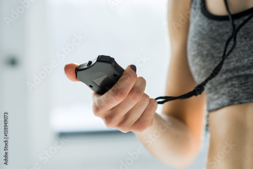 partial view of sporty woman holding stopwatch in hand