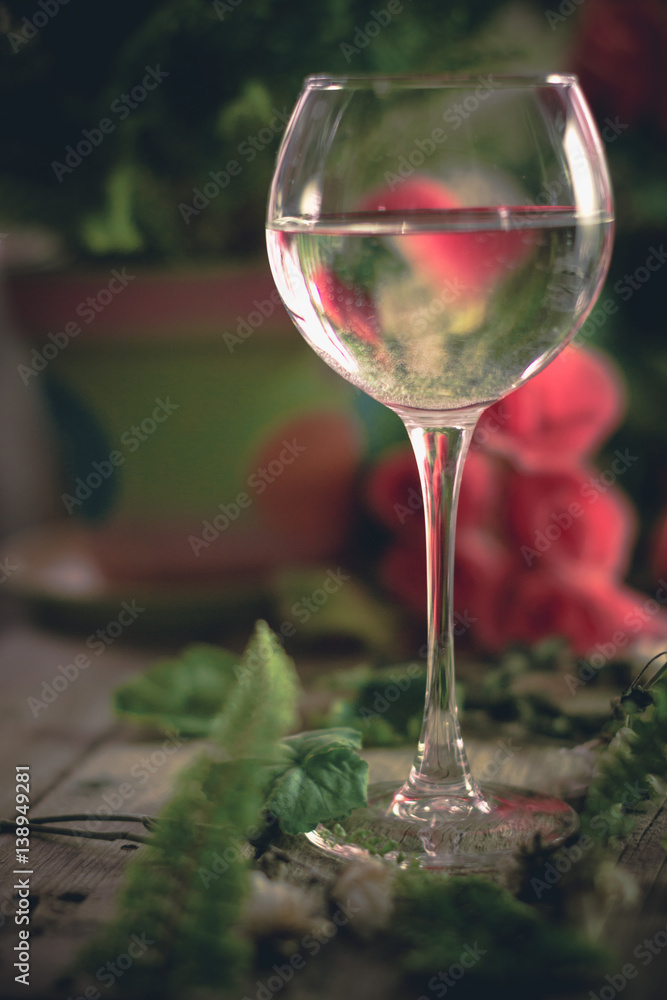 A glass of water on the flowers and plants against A glass of water on the flowers and plants against