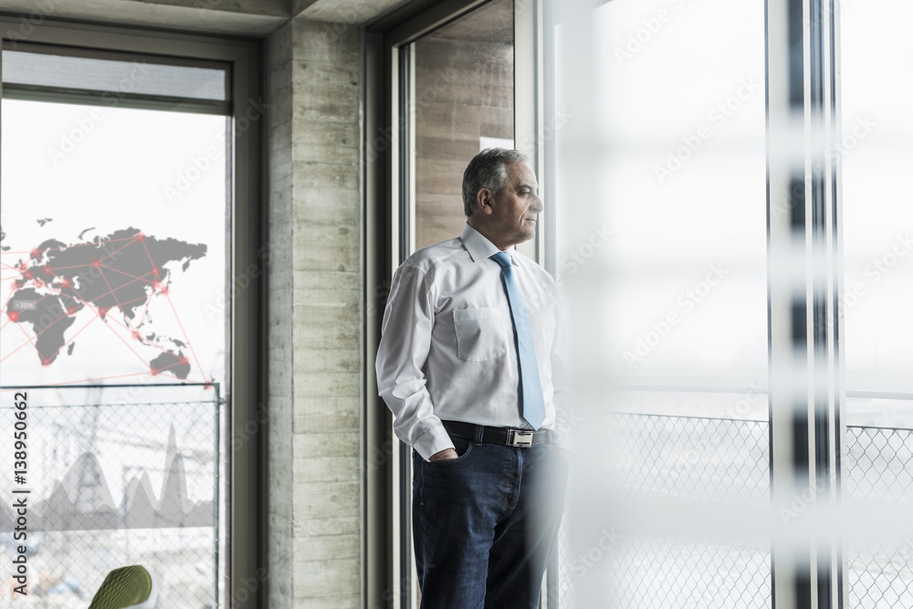 Businessman looking out of window in office Businessman looking out of window in office