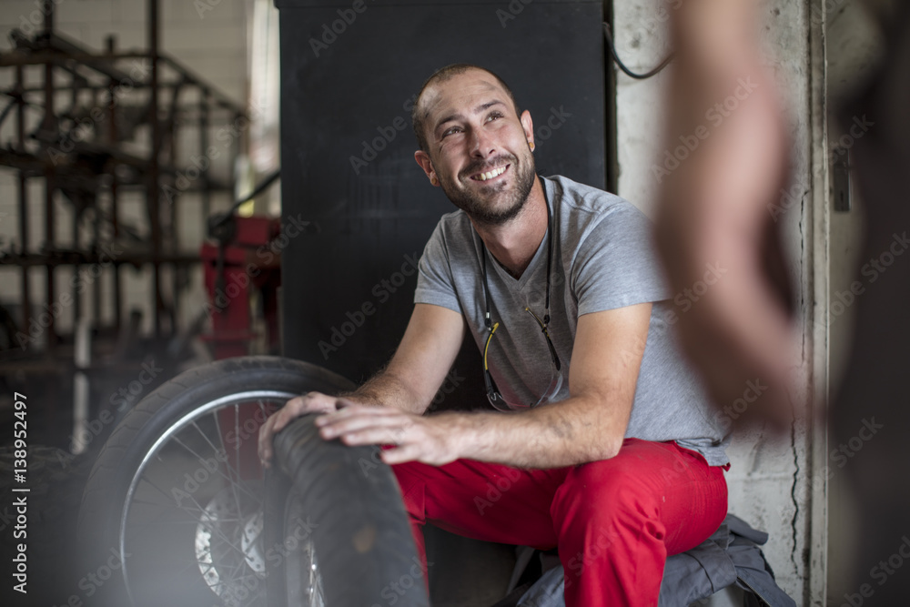 Smiling mechanic in workshop looking at colleague Smiling mechanic in workshop looking at colleague