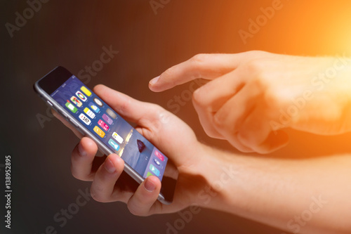 Hand holding black smartphone with operating system screen