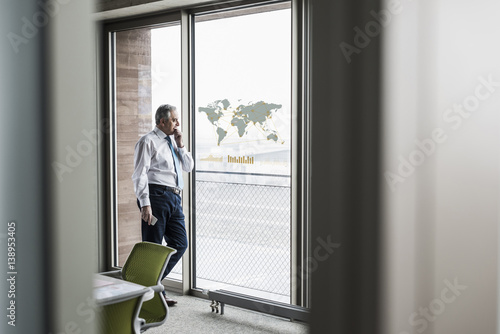 Businessman looking at windowpane with world map in office © Westend61