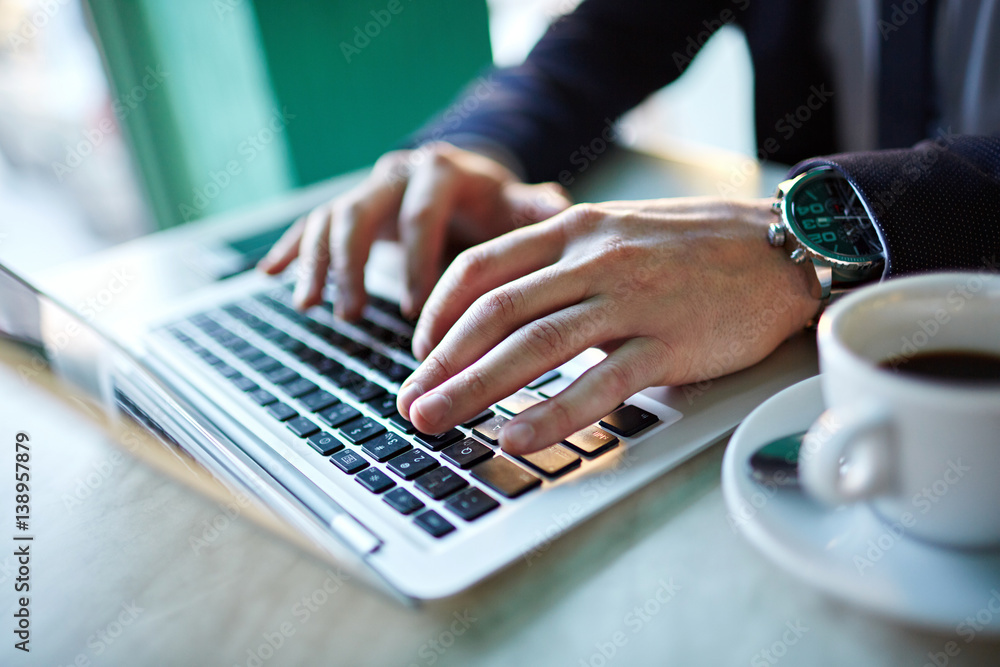 Closeup shot of male hands of successful businessman with expensive wristwatch typing while working at laptop Closeup shot of male hands of successful businessman with expensive wristwatch typing while working at laptop