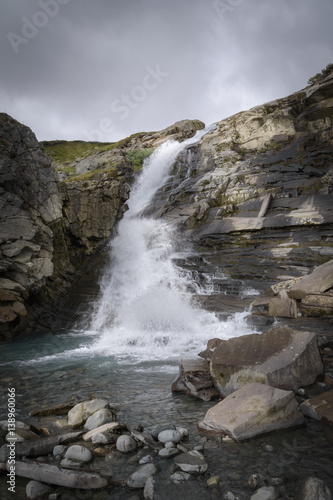 Waterfall catching the sunlight in layered rock landscape