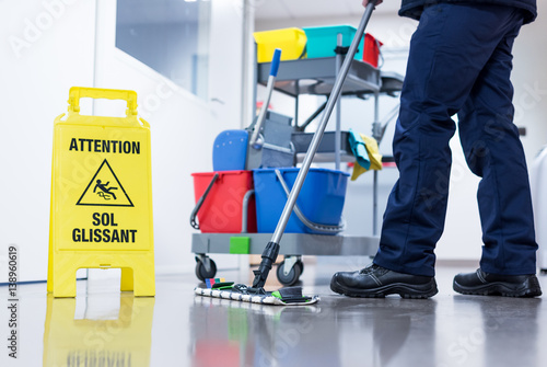 Worker janitor Mopping Floor In Office with trolley