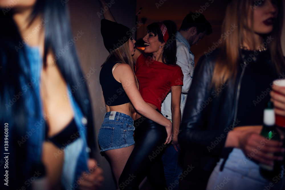 Sneak shot of crowded dark club, semi naked young people partying and drinking beer with two beutiful girls dancing in background Stock Photo Adobe Stock