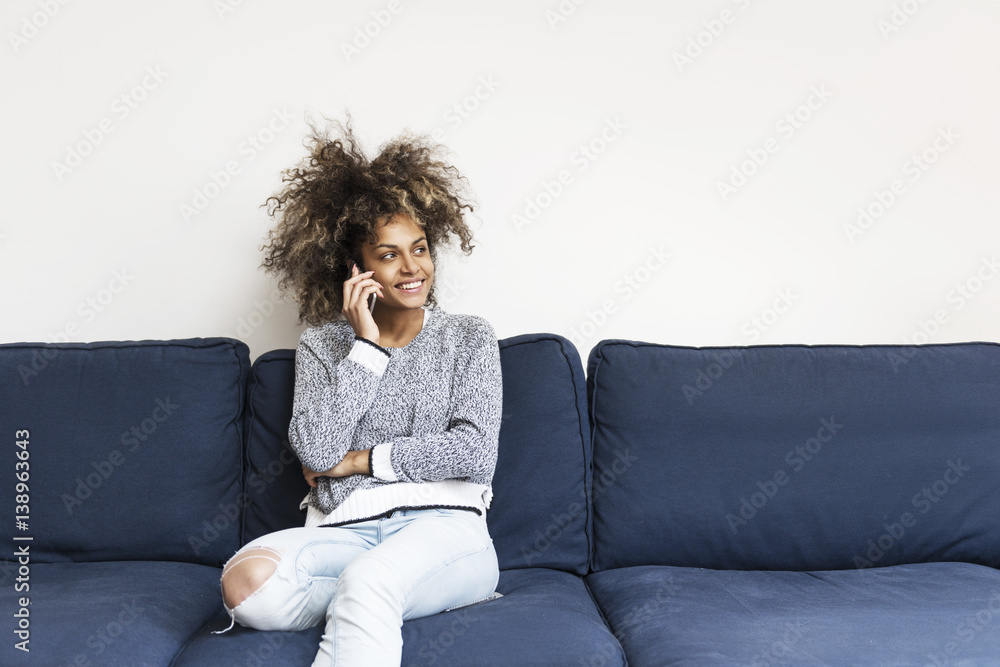 Beautiful African American woman sitting on the sofa using a cell phone Beautiful African American woman sitting on the sofa using a cell phone