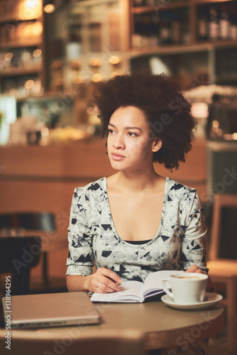 Mixed race woman in coffee shop having coffee and smiling