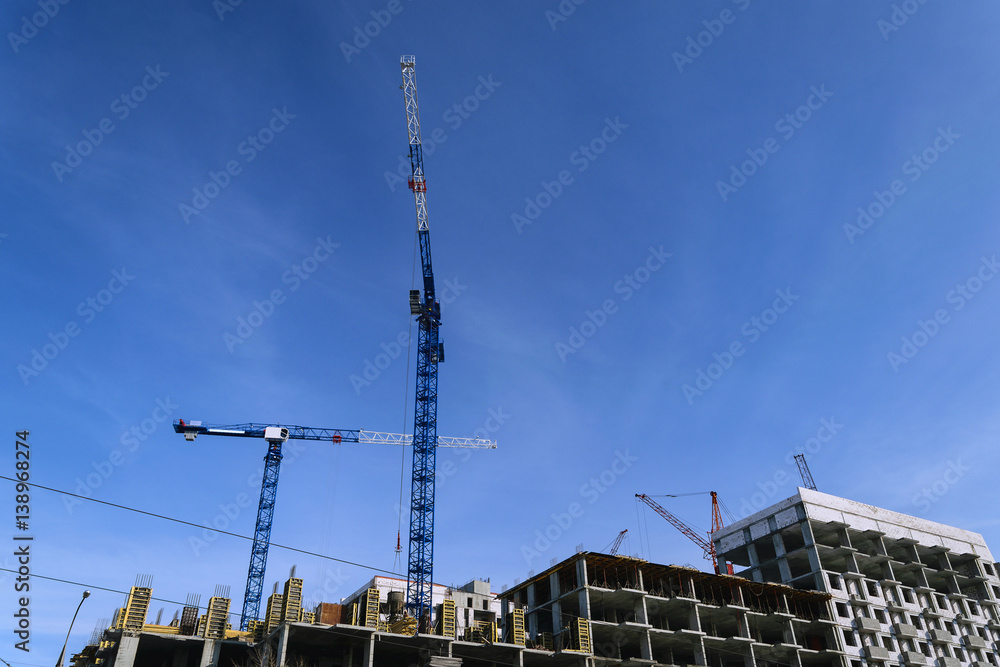 constructionsite with two bulding cranes against blue sky constructionsite with two bulding cranes against blue sky
