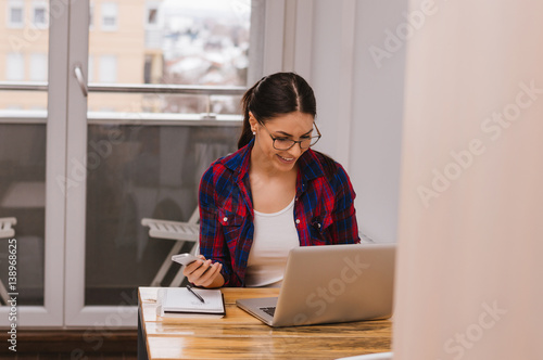 Woman using mobile phone and laptop at home