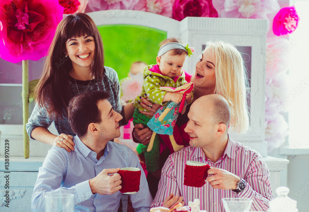 Charming young women stand behind their husbands drinking tea at dinner table Charming young women stand behind their husbands drinking tea at dinner table