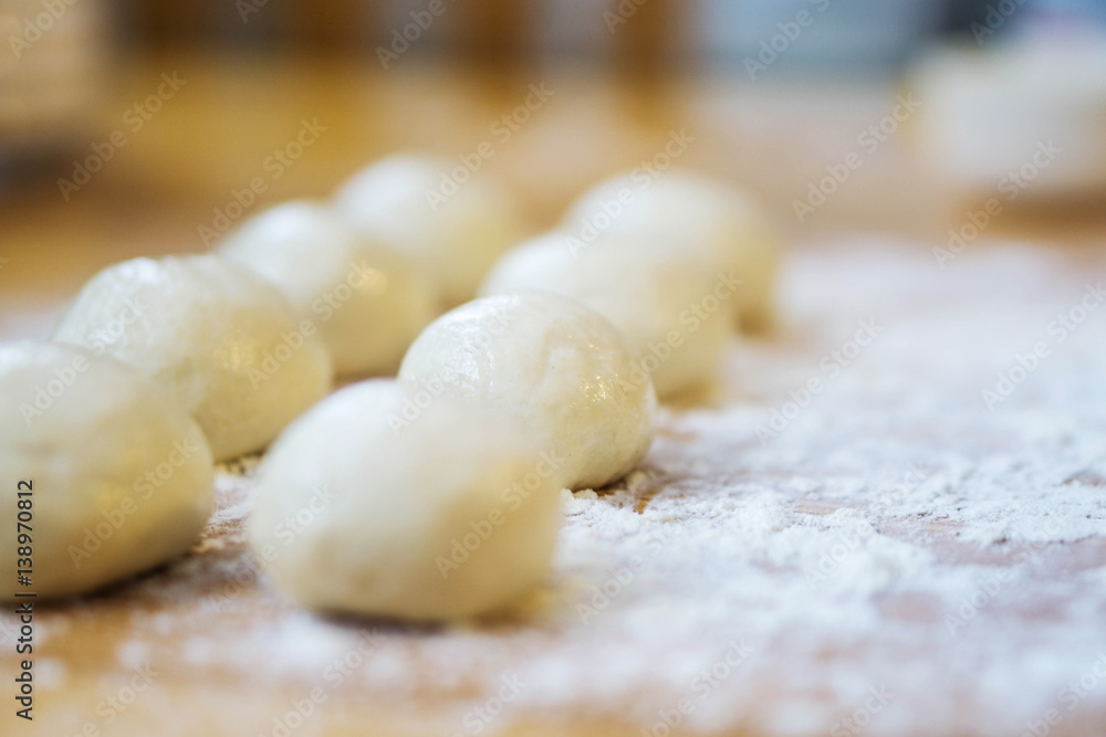 Closeup of small balls ready dough on floured kitchen table. Defokus in the background.