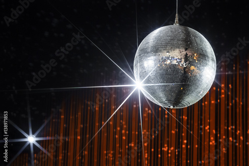 Disco ball with stars in nightclub with striped orange and black walls lit by spotlight, party and nightlife entertainment industry 