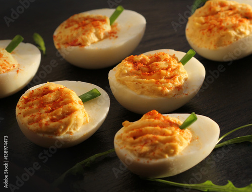 deviled eggs with red pepper on black background