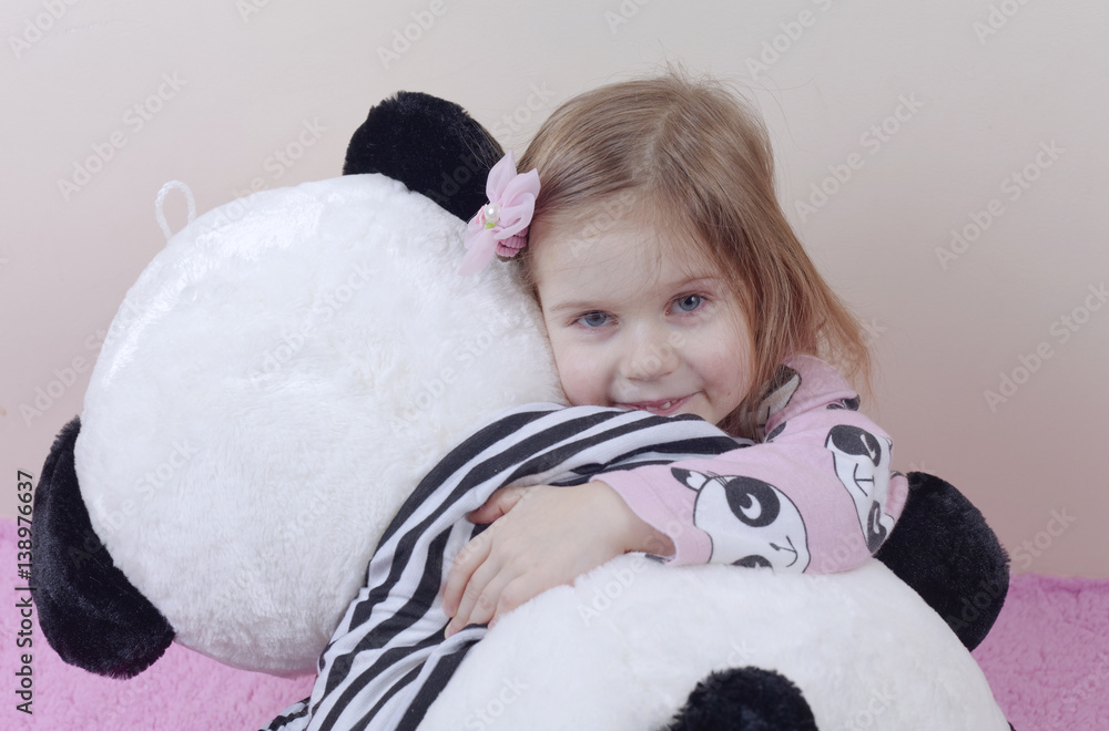 Adorable little girl in nightgown playing with her soft toy panda. Child is happy with her bear. Tinted photo. Adorable little girl in nightgown playing with her soft toy panda. Child is happy with her bear. Tinted photo.