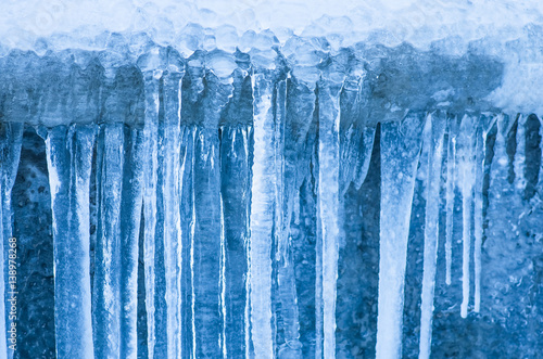 Icicles hanging against a background of wall © fotolesnik