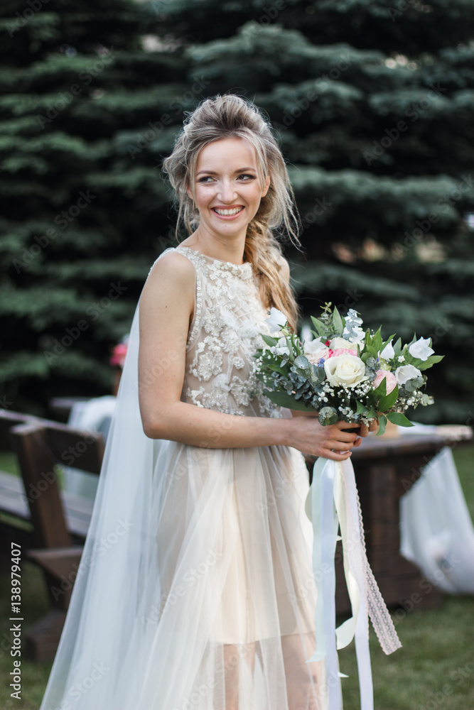 Attractive bride posing with bridal nosegay on open air looking at camera Attractive bride posing with bridal nosegay on open air looking at camera