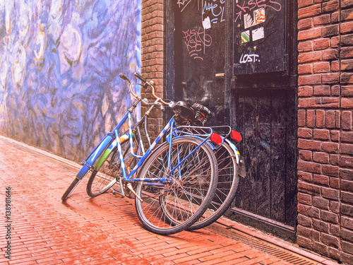 Two bicycles leaning against the door on the stone-paved roadway.
Picture with artistic treatment.
