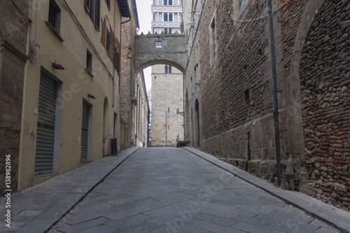 Ancient street and Campanile del Duomo di Pistoia on background. Tuscany. Italy.