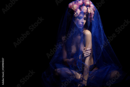 beautiful sexy girl with black hair with a wreath of flowers sdit Subfam blue veil on the head with bare shoulders in the studio on a black background with photo