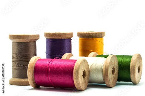 Isolated wooden spools of thread with a needle