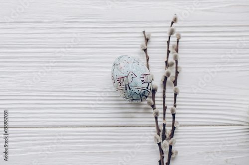 happy easter greeting card. simple easter egg with chick ornaments and willow buds on rustic white wooden desk background. with space for text  top view. soft light