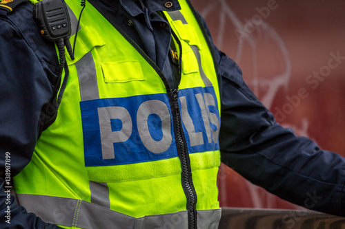 Close up of Swedish police officer wearing a luminous yellow green vest with police text. 