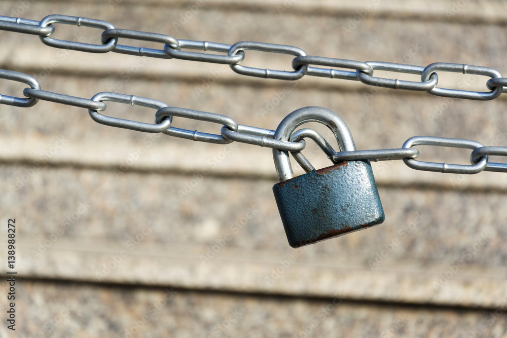 Blue metallic padlock hangs on silver iron chain with stairs Blue metallic padlock hangs on silver iron chain with stairs