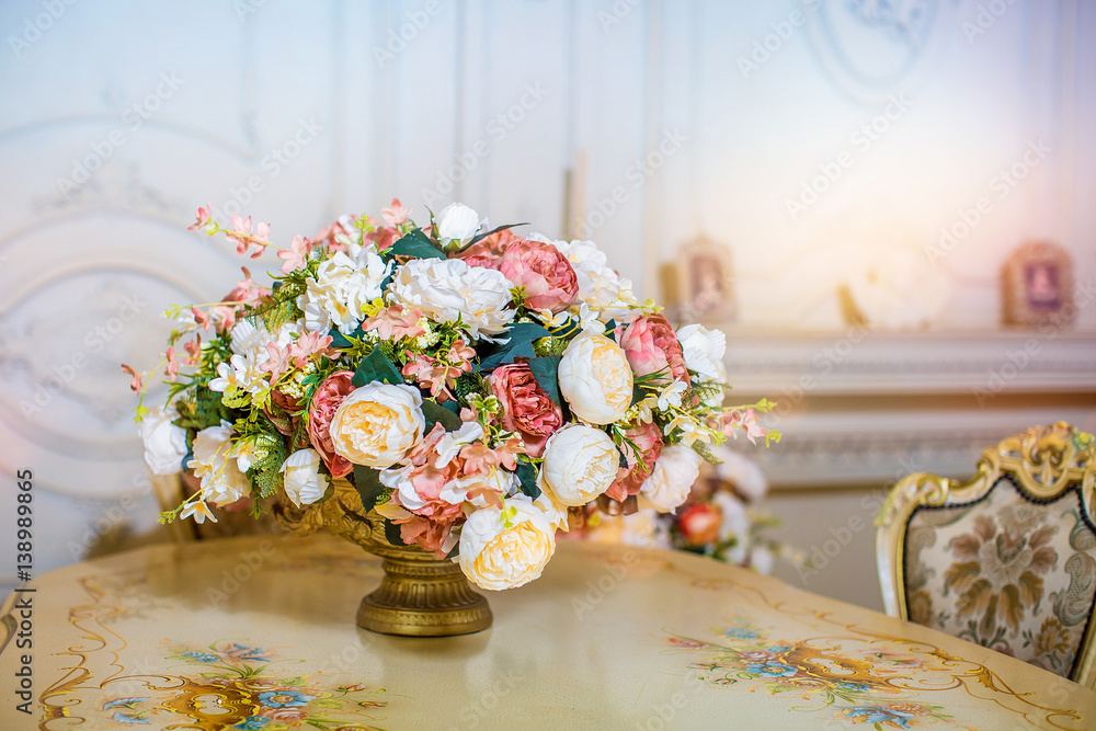 Beautiful elegant artificial bouquet of flowers are in vase on table