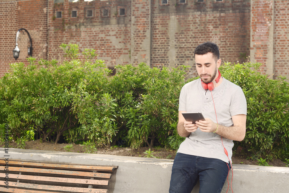 Obraz premium Young man using tablet with headphones.