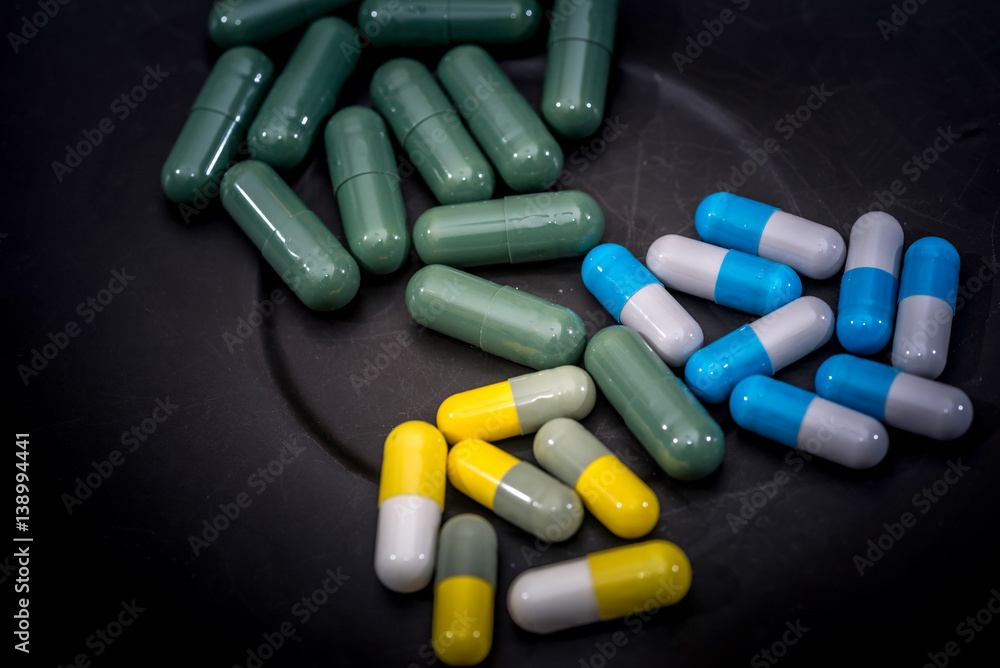 Medicine pills or capsules on plate on wooden desk with copy space.