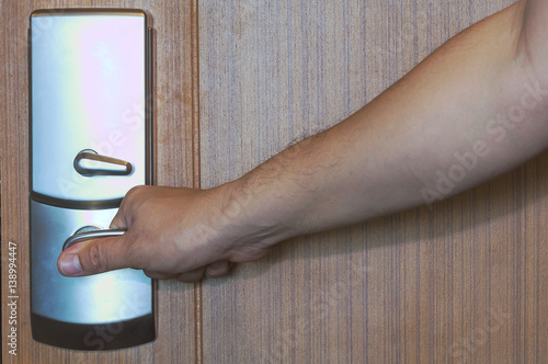 Fotografi Door lock of wooden door being opening by hand