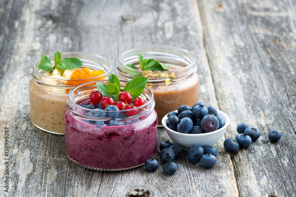 assortment breakfast with fresh berries, fruit and chocolate in glass jars on wooden table assortment breakfast with fresh berries, fruit and chocolate in glass jars on wooden table