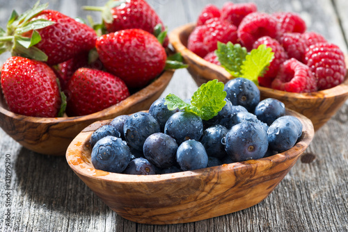 assortment of fresh seasonal berries in a wooden bowl, closeup