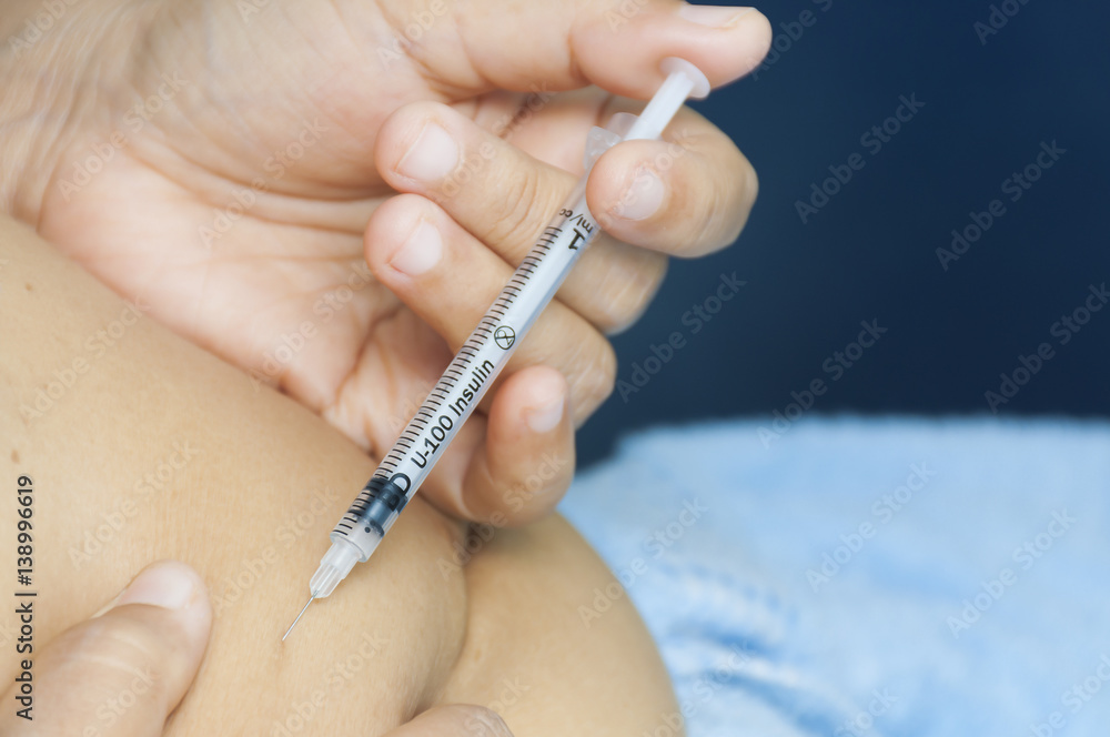 A lady is injecting insulin into her stomach. Photo is focus at syringe. A lady is injecting insulin into her stomach. Photo is focus at syringe.