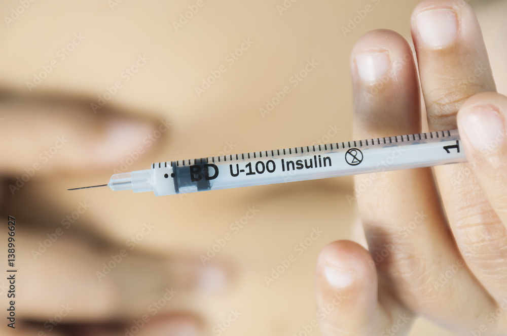 A lady is injecting insulin into her stomach. Photo is focus at syringe. A lady is injecting insulin into her stomach. Photo is focus at syringe.