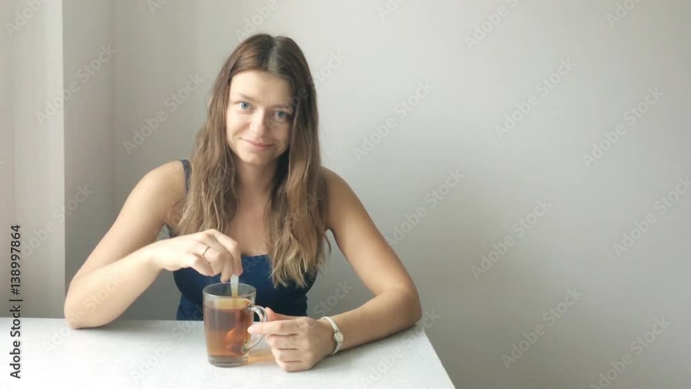 Portrait of a beautiful young woman without makeup with blonde hair prevents spoon tea Portrait of a beautiful young woman without makeup with blonde hair prevents spoon tea