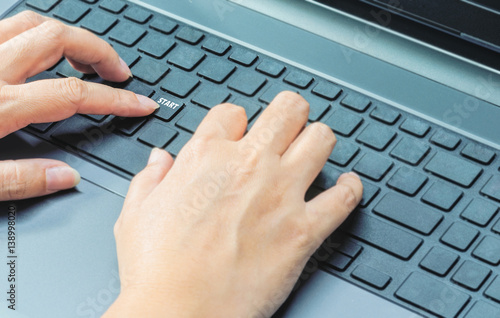 Female fingers press at start button on a laptop keyboard, business office concept
