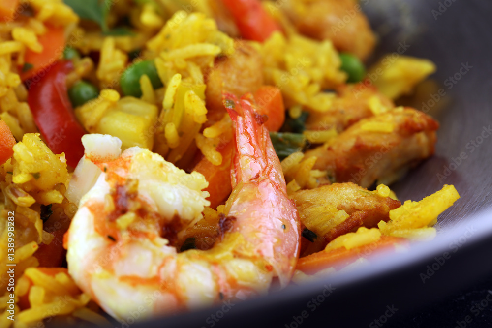 Udon stir-fry rice with shrimp and vegetables in wok pan on black burned stone background Udon stir-fry rice with shrimp and vegetables in wok pan on black burned stone background