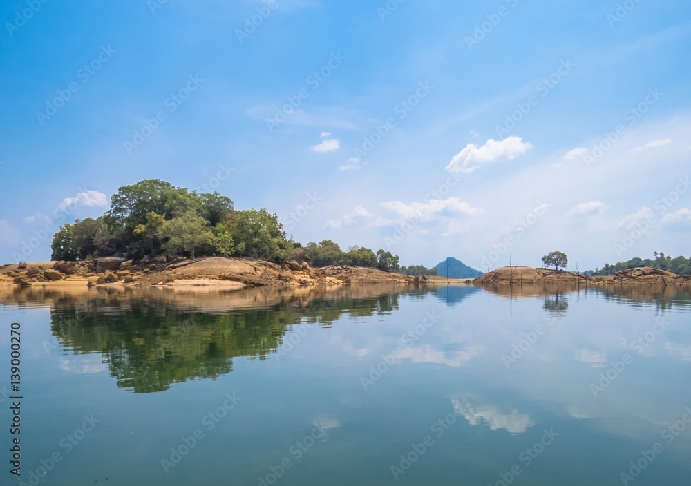 Reflection on a Lake of Beautiful Island Trees land with rocks with bluesky and clouds in Sri Lanka