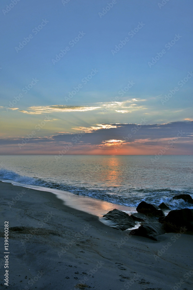Fototapeta premium Scenic Summer Seashore Sunrise Over Rock Jetty on the Beach