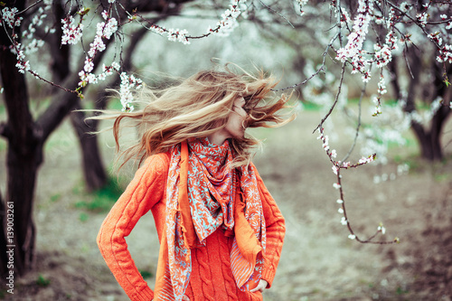 Fototapeta Girl hair develops on the background of blooming trees, positive