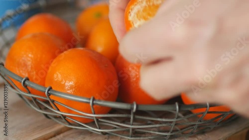 Man peeling clementine against a basket with fruits