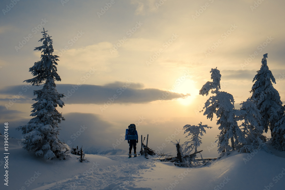 Man hiking in beautiful winter mountain at golden sunset