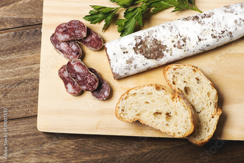 General shoot of fuet and bread  on a wooden board. Spanish sausage. Horizontal shoot. photo