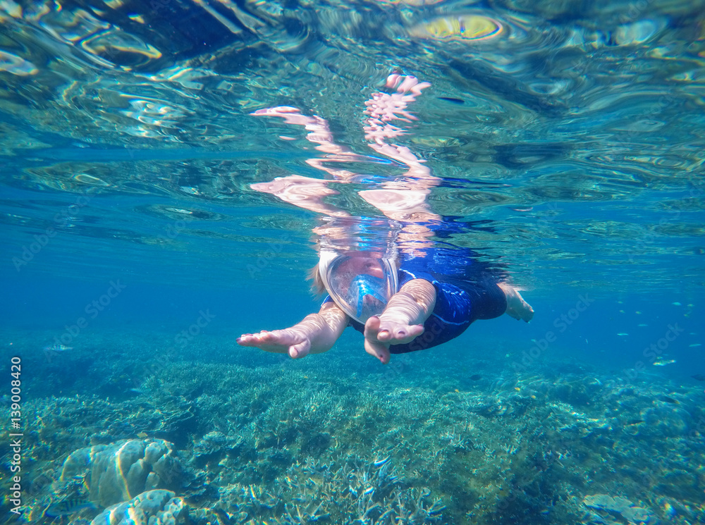 Woman swimming underwater in swimming costume and full-face mask