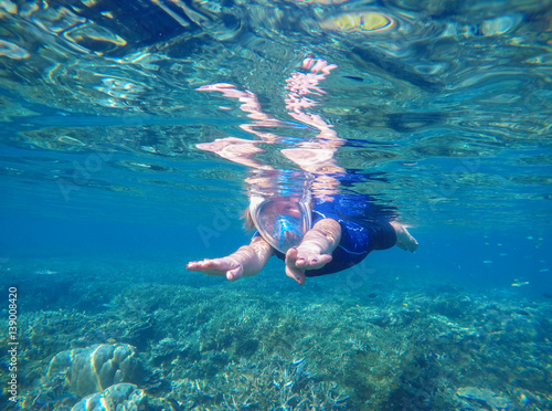 Woman swimming underwater in swimming costume and full-face mask
